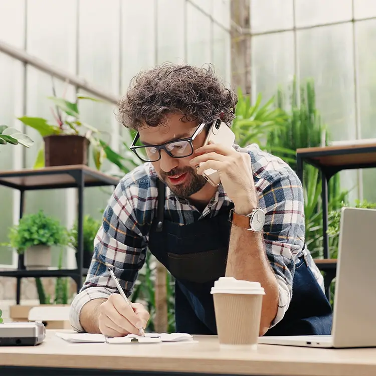 a man in a greenhouse trying to work out holiday pay while talking to employer advice.