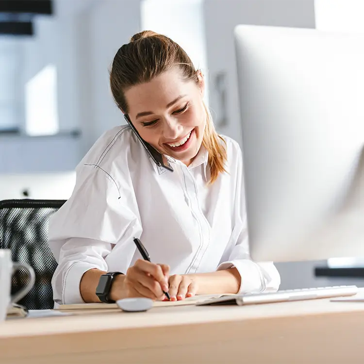 a woman on the phone while taking notes.